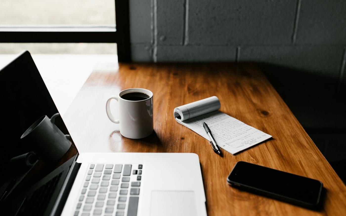 Ordinateur portable, carnet et tasse de café sur un bureau en bois